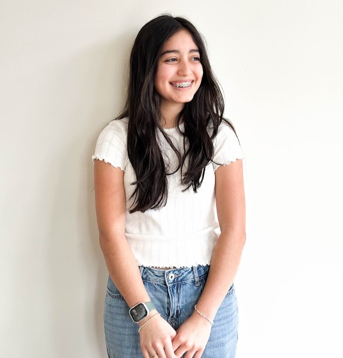 Smiling teen standing against a light wall